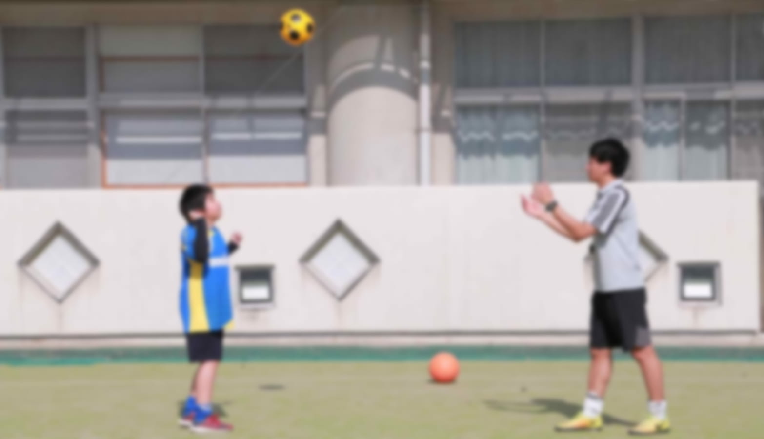 生徒とサッカーの練習をする鈴木ゆうきコーチの写真 - 障がい児のためのサッカースクール
